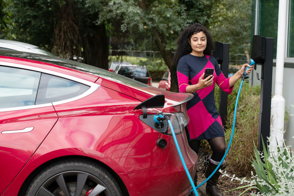 Woman next to electric car charging