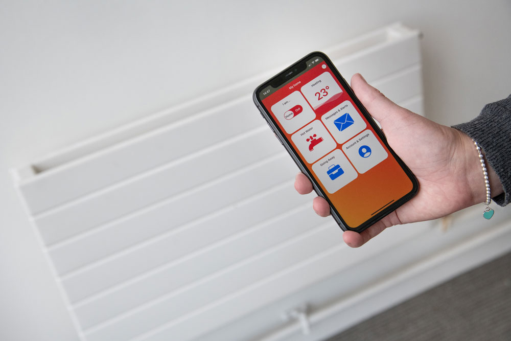 Woman holding mobile with Passiv app displayed next to radiator