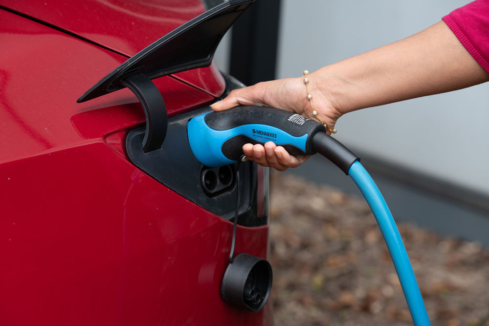 Woman connecting electric charger to car